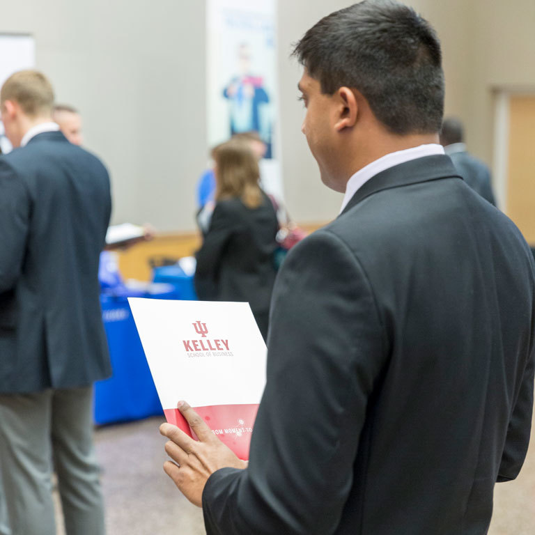 An accounting student holds a red IU Kelley School of Business folder at a career fair.